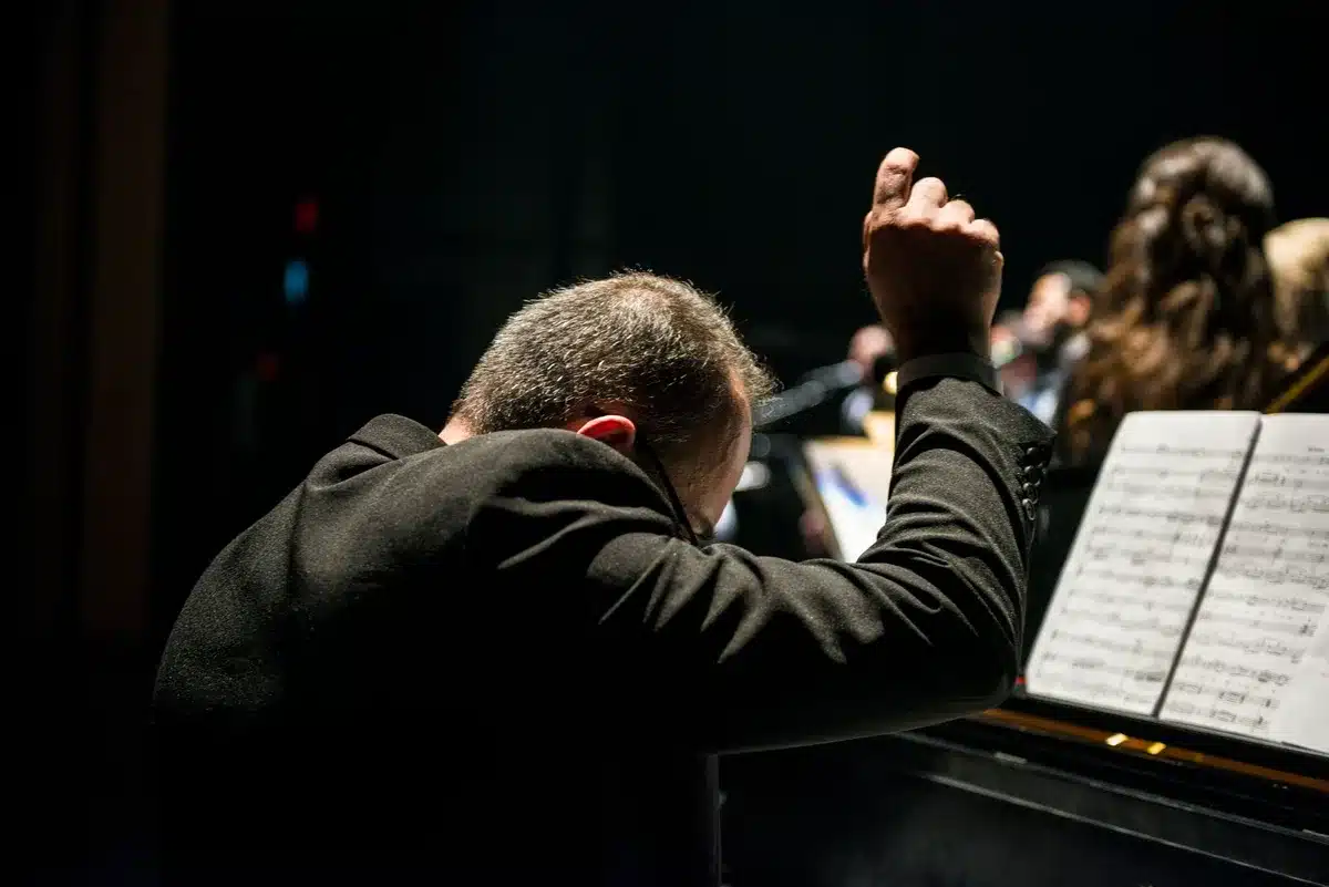 Orchestra musicians performing live with conductor leading ensemble during a concert performance