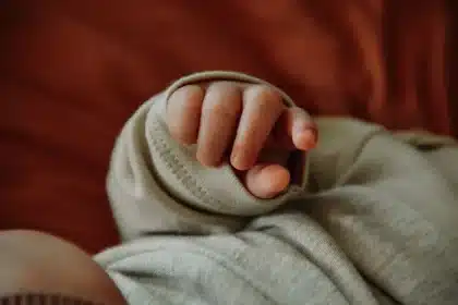 Hands gently holding a newborn baby wrapped in soft blankets