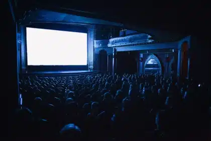 Moviegoers in a theater lobby with popcorn and tickets during a busy weekend
