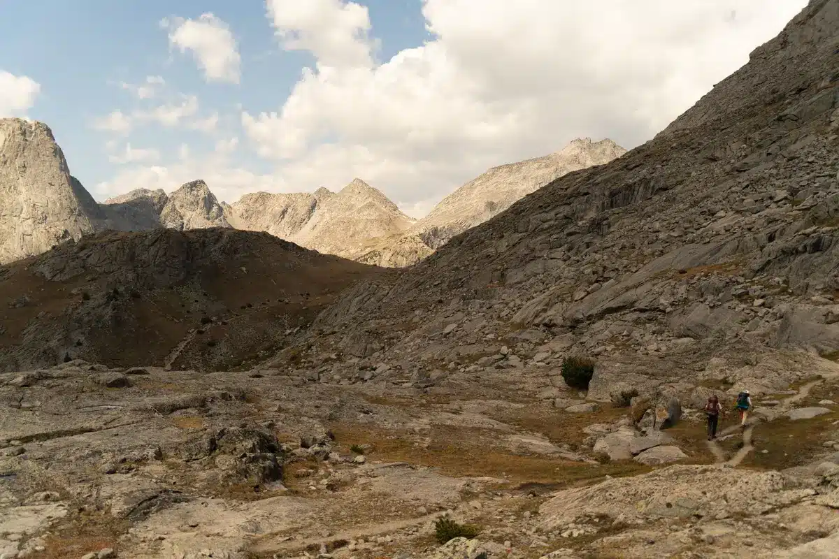 Person hiking through rocky wilderness with mountains in background