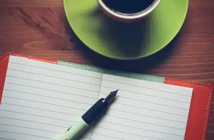 Morning workspace with coffee, notebook and phone on desk with natural light