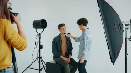 Makeup artist applying foundation to an actor's face in a professional studio with bright lighting