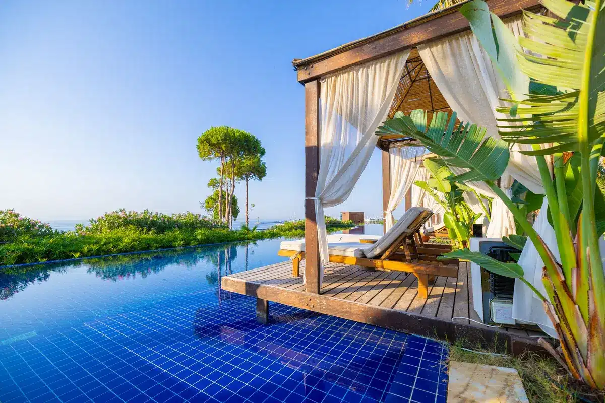 Sprawling outdoor pool area with private cabanas overlooking a tropical marina at a luxury Caribbean resort