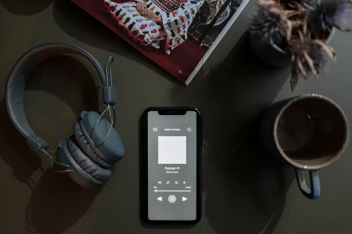 Person using a streaming app on mobile phone with headphones for listening to audio content