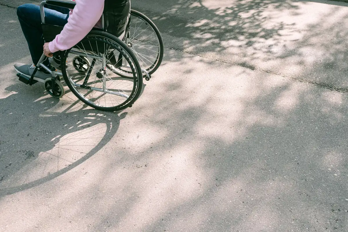 Una persona usando una silla de ruedas con apoyo de un cuidador en un entorno accesible