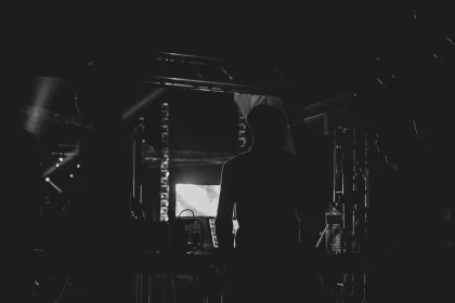 Silhouette of a performer on stage under dramatic concert lighting and projections