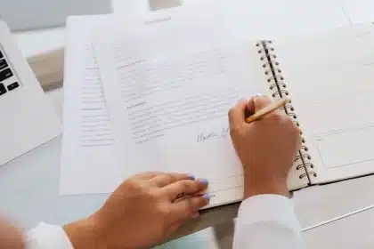 Person reviewing payment documents and contracts at a desk with lamp lighting