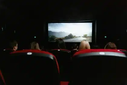 Silhouette of a hand pointing at a blank cinema screen in a dark theatre