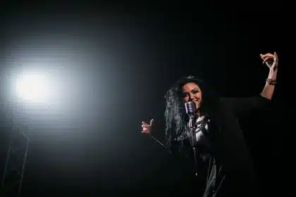 Silhouetted performer at microphone under warm stage lighting in an empty venue