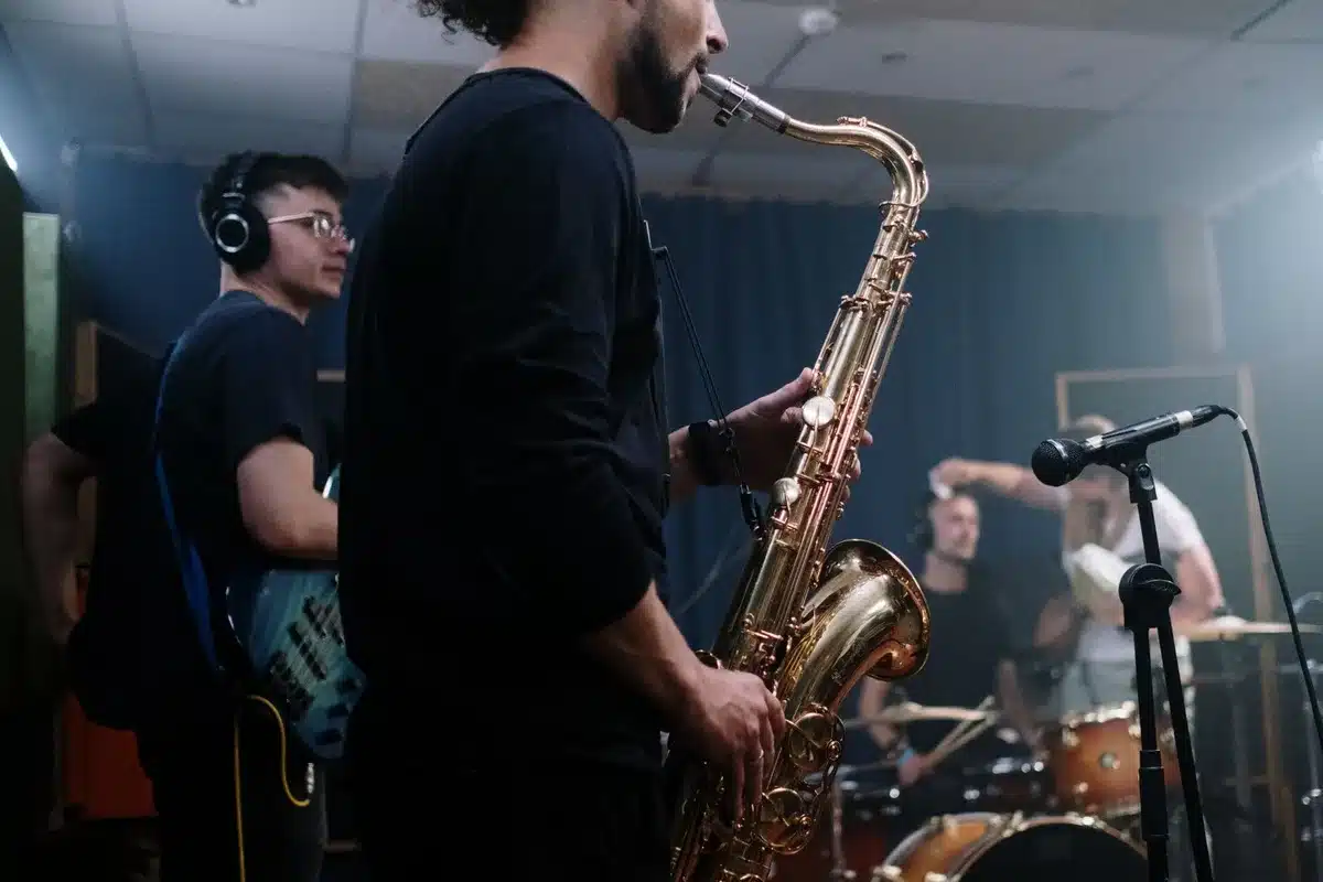 Musicians recording in a studio with orchestral instruments and mixing equipment