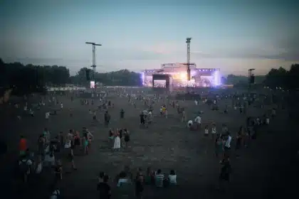 Silhouettes of musicians performing on stage at a festival with audience below