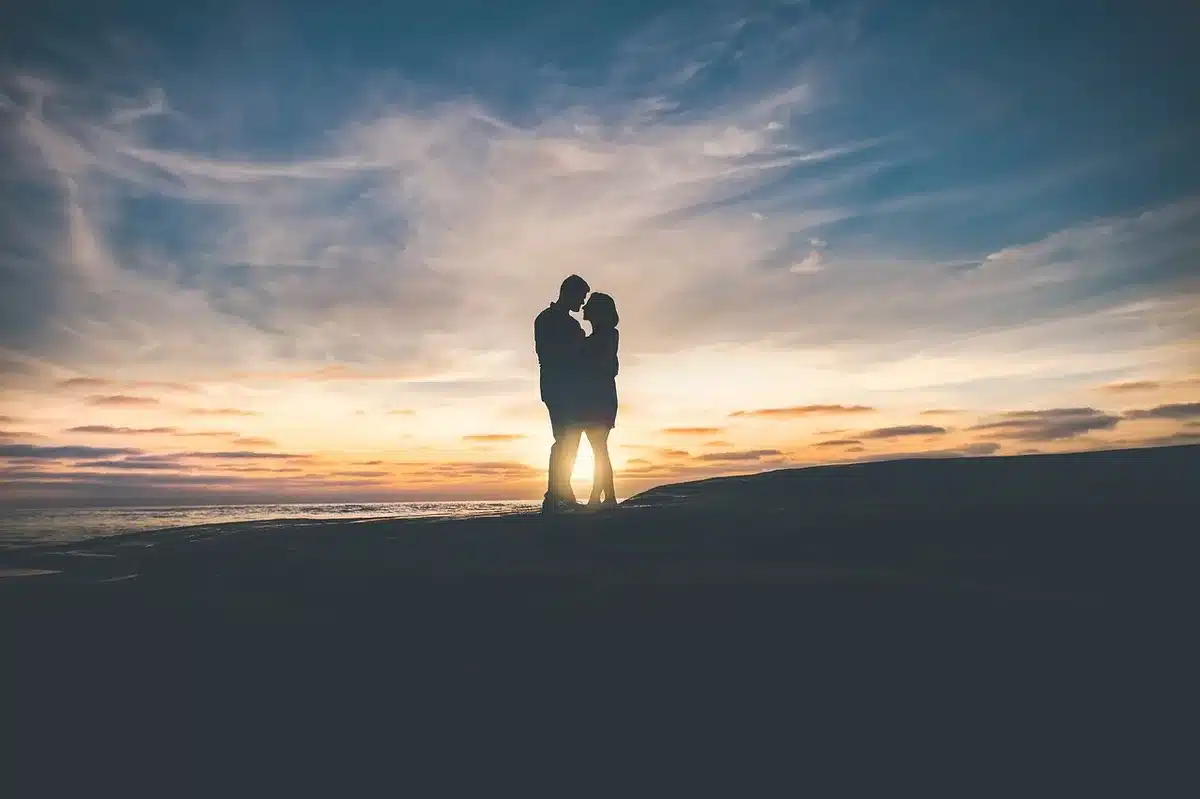 Silhouetted couple standing apart on a porch with moving boxes, late afternoon light