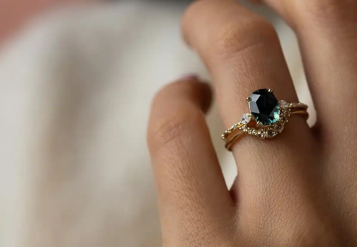 Close-up of high-jewelry earrings and rings on a red-carpet gown cuff