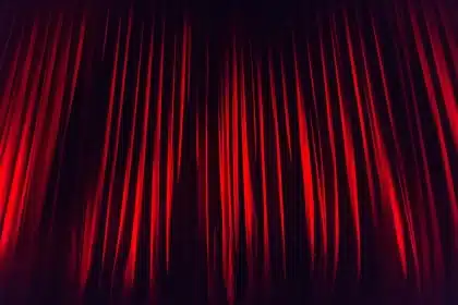 Mariachi ensemble rehearsing on a small civic stage with audience silhouettes