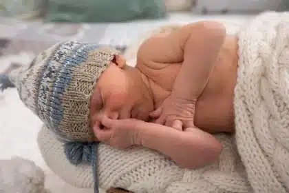 Enfant regardant la télévision assis sur un canapé enveloppé dans une couverture