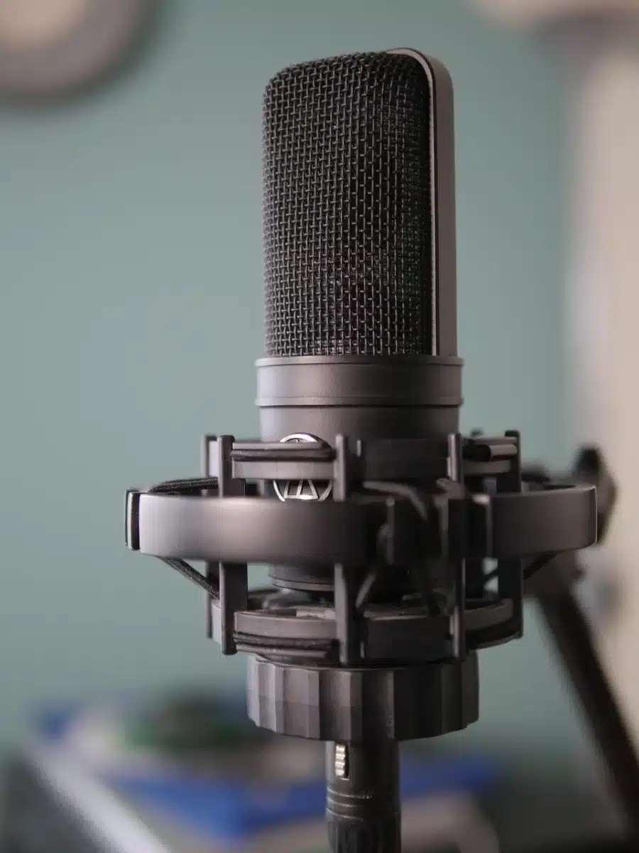 Session pianist's hands at piano keys in a professional recording studio with microphone and booth visible