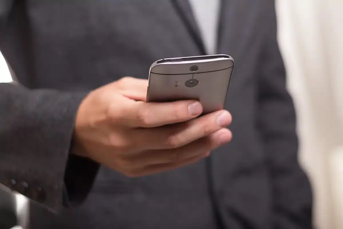 Hands holding a phone showing a bold campaign-style text on social feed