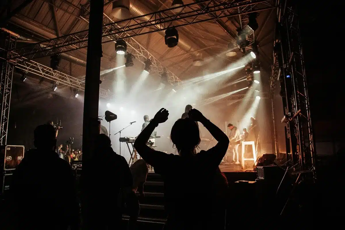Festival stage with schedule board and audience, showing changed start times